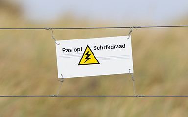 Image showing Border fence - Old plastic sign with a flag