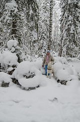 Image showing The woman with a dog on walk in a winter wood