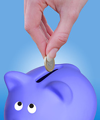 Image showing Putting a coin euro in a piggy bank
