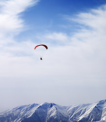 Image showing Paraglider silhouette of mountains in windy sky at sun day