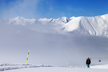 Image showing Snowboarder on off-piste slope and mountains in mist