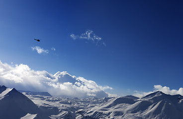 Image showing Helicopter above snowy plateau and sunny sky