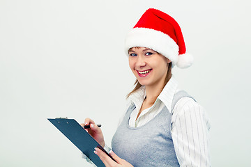 Image showing happy girl in santa hat with a notebook