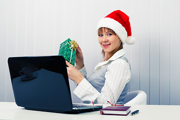 Image showing girl in the office in Santa hats with a laptop and a gift