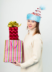 Image showing happy girl in an unusual Christmas hat with gift boxes