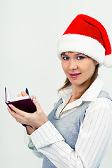 Image showing happy girl in santa hat with a notebook