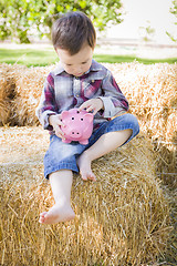 Image showing Cute Young Mixed Race Boy Putting Coins Into Piggy Bank