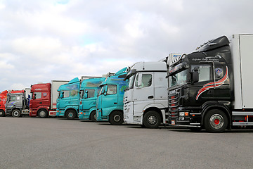 Image showing Row of Colorful Trailer Trucks on a Yard