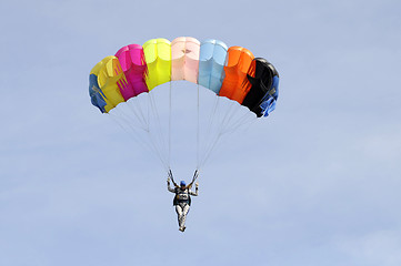 Image showing the parachutist goes down on a multi-colored parachute.