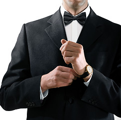 Image showing man in tuxedo puts on watch