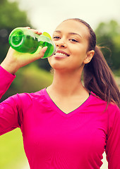 Image showing smiling woman drinking from bottle