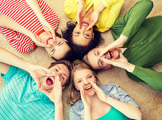 Image showing smiling people lying down on floor and screaming