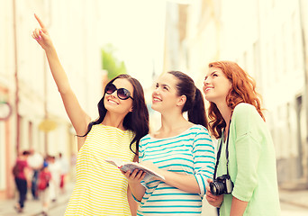 Image showing smiling teenage girls with city guide and camera