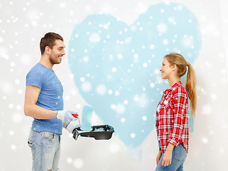 Image showing smiling couple painting big heart on wall