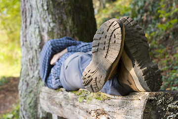 Image showing Hiker lying on a wooden bench