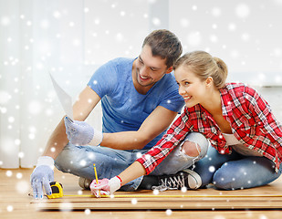 Image showing smiling couple measuring wood flooring