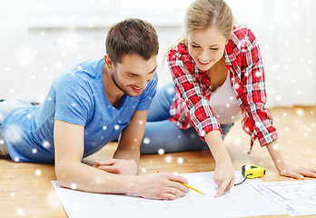 Image showing smiling couple with  blueprint at home