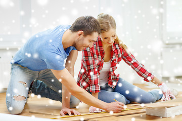 Image showing smiling couple measuring wood flooring