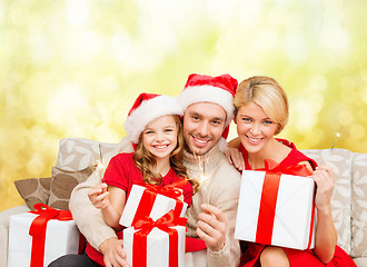 Image showing smiling family holding gift boxes and sparkles