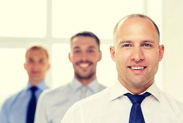 Image showing smiling businessman in office with team on back