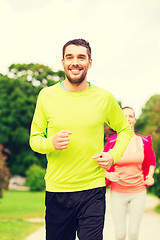 Image showing smiling couple running outdoors