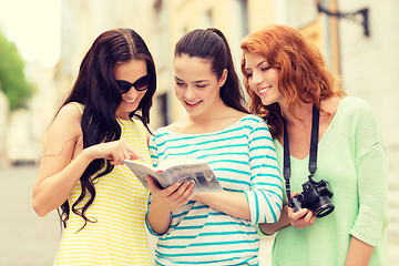 Image showing smiling teenage girls with city guide and camera