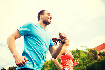 Image showing smiling couple running outdoors