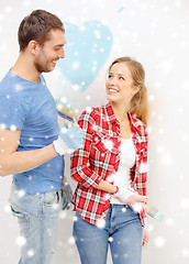 Image showing smiling couple painting small heart on wall