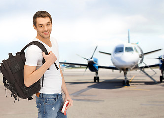 Image showing smiling student with backpack and book at airport