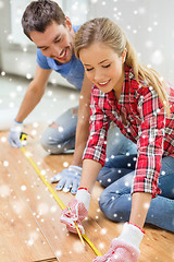 Image showing smiling couple measuring wood flooring