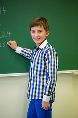 Image showing little smiling schoolboy writing on chalk board