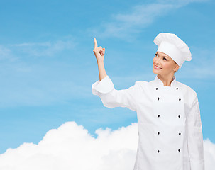 Image showing smiling female chef pointing finger to something