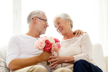 Image showing happy senior couple with bunch of flowers at home