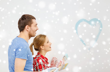 Image showing smiling couple painting small heart on wall