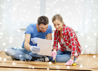 Image showing smiling couple measuring wood flooring