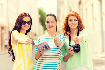 Image showing smiling teenage girls with city guide and camera