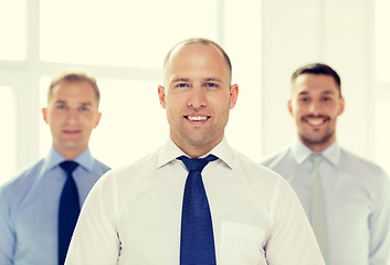 Image showing smiling businessman in office with team on back