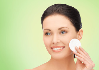 Image showing smiling woman cleaning face skin with cotton pad