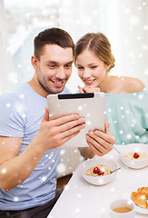 Image showing smiling couple with tablet pc having breakfast