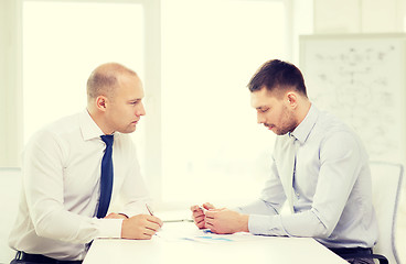 Image showing two serious businessman with papers in office