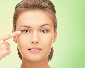 Image showing beautiful young woman pointing finger to her eye