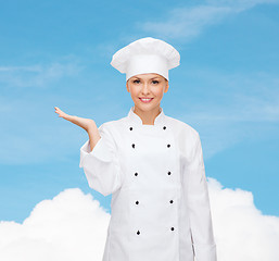 Image showing smiling female chef holding something on hand