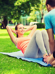 Image showing smiling woman doing exercises on mat outdoors