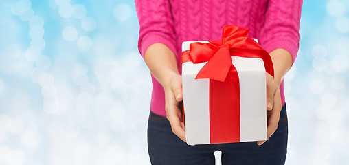 Image showing close up of woman in pink sweater holding gift box