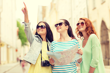 Image showing smiling teenage girls with map and camera