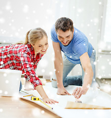 Image showing smiling couple smearing wallpaper with glue