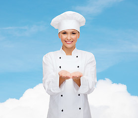 Image showing smiling female chef holding something on hands