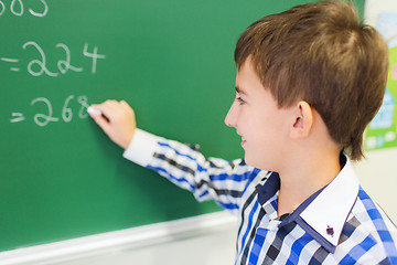 Image showing little smiling schoolboy writing on chalk board