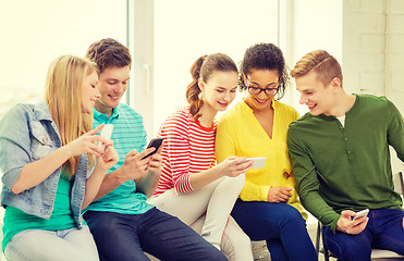 Image showing smiling students with smartphone texting at school