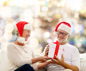 Image showing happy senior couple in santa hats with gift box